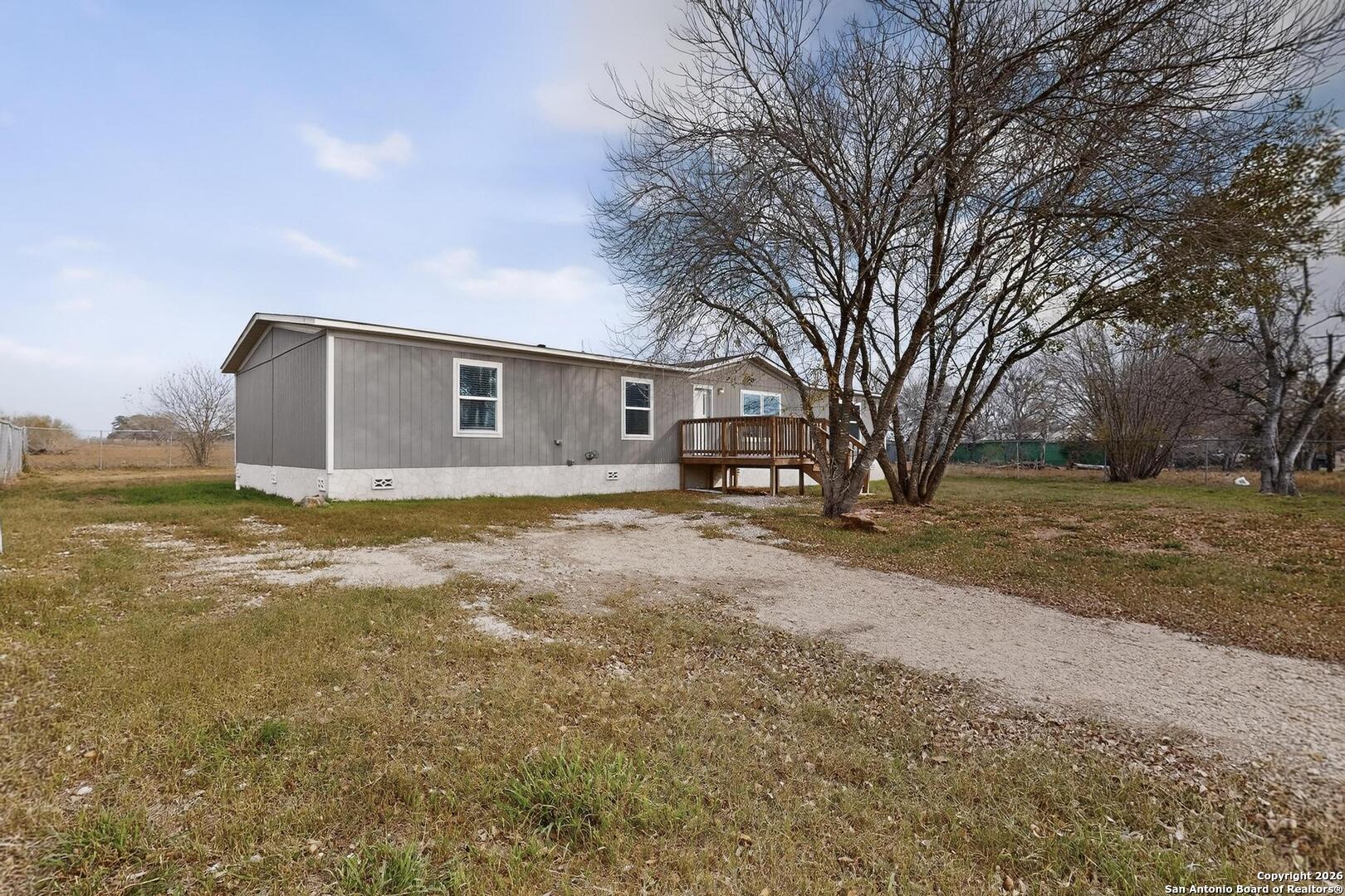 19124 La Gloria Road Elmendorf, TX 78112 - Photo 37 of 45 a backyard of a house with large trees and a small yard