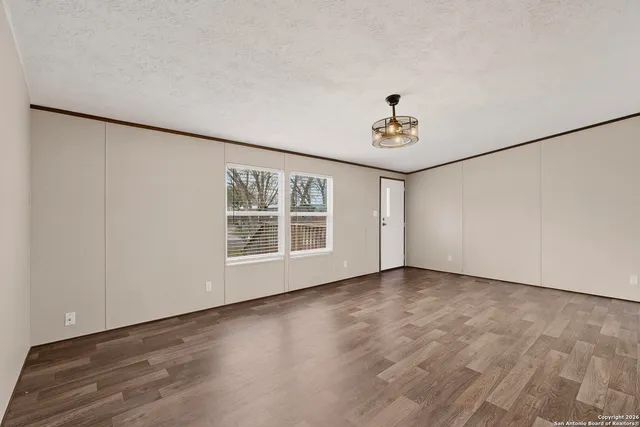 an empty room with windows and ceiling fan