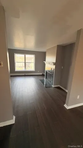 a view of empty room with wooden floor and fireplace