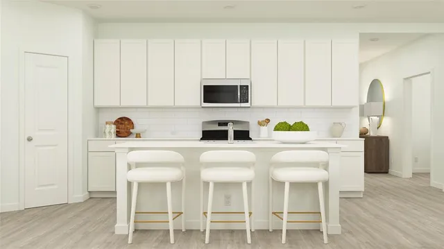 a white kitchen with a sink a stove and white cabinets