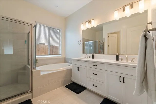 a bathroom with a tub a sink double vanity and a mirror