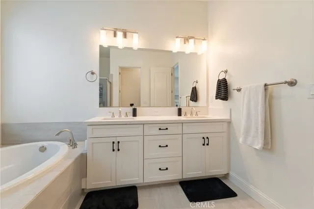 a bathroom with a double vanity sink a mirror and a bathtub