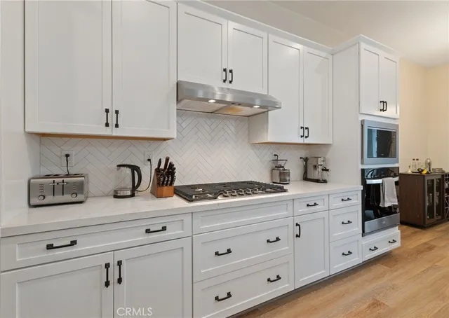 a kitchen with granite countertop white cabinets and stainless steel appliances