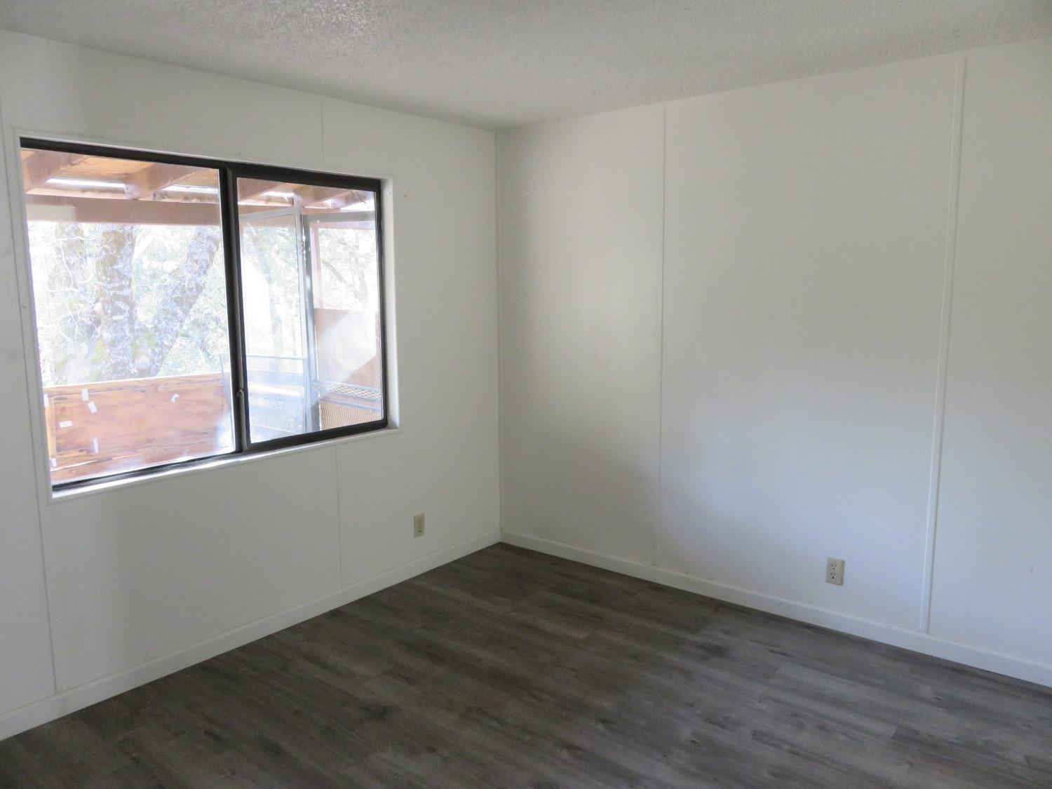 4426 Bald Mountain Road West Point, CA 95255 - Photo 28 of 45 a view of an empty room with wooden floor and a window