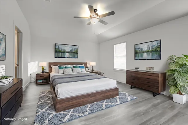 a spacious bedroom with a bed painting on wall and a potted plant