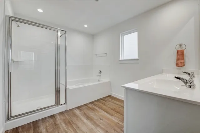 a bathroom with a bathtub shower sink vanity and mirror