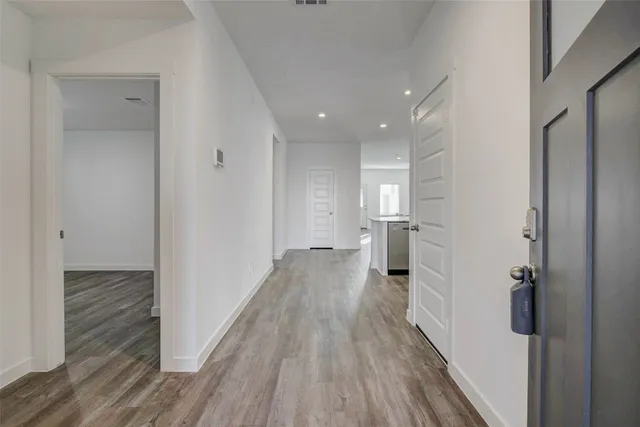 a view of a hallway with wooden floor and a bathroom