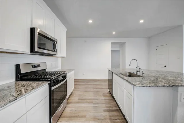 a kitchen with granite countertop sink stainless steel appliances and cabinets
