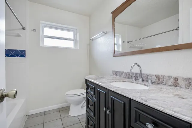a bathroom with a granite countertop sink a toilet and a mirror