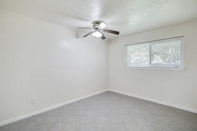 an empty room with a window and a fan