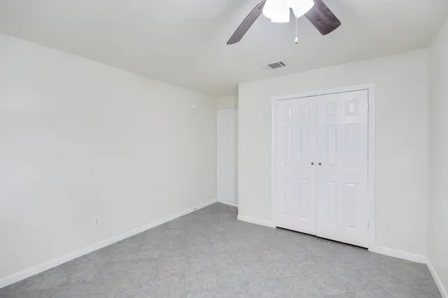 an empty room with a ceiling fan and a window
