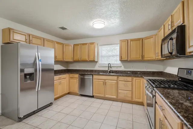 a kitchen with stainless steel appliances granite countertop a stove top oven a sink and dishwasher