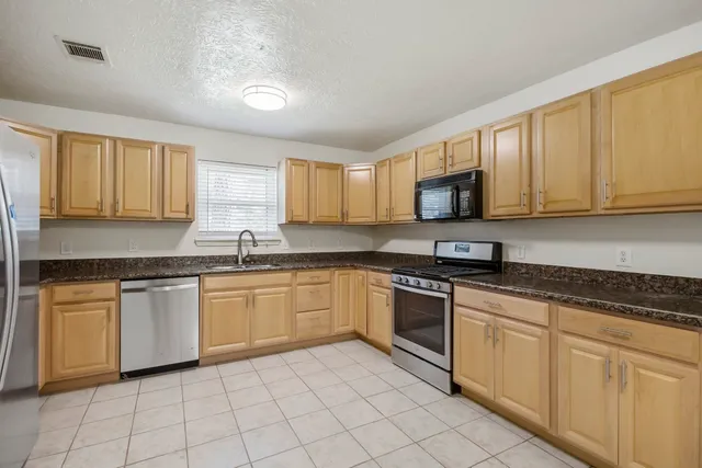 a kitchen with granite countertop white cabinets white stainless steel appliances with a sink and dishwasher