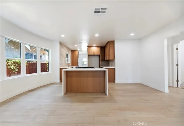 a view of kitchen with kitchen island stainless steel appliances refrigerator sink and cabinets