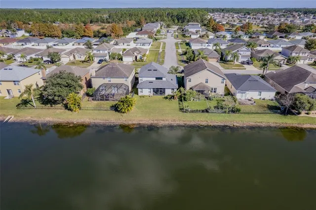an aerial view of residential houses with outdoor space and lake view