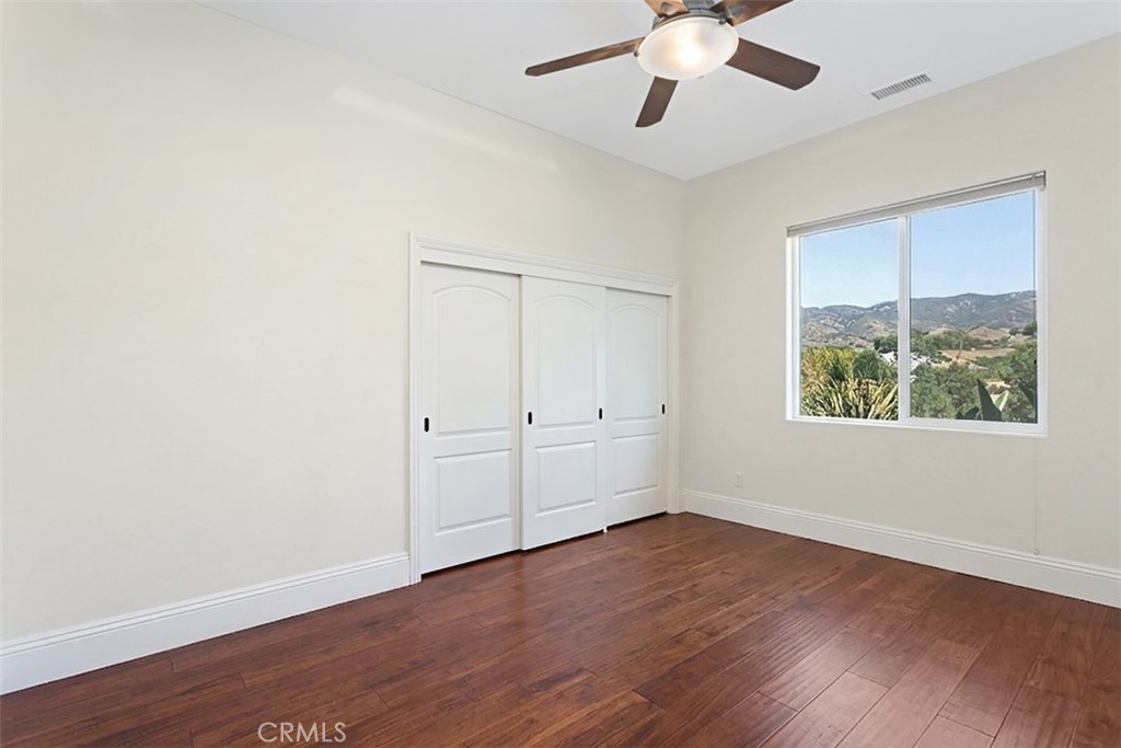 4106 Rock Mountain Road Fallbrook, CA 92028 - Photo 21 of 36 an empty room with wooden floor chandelier fan and windows