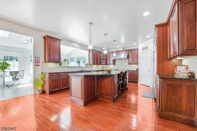 a kitchen with stainless steel appliances kitchen island granite countertop wooden floors and a view of living room
