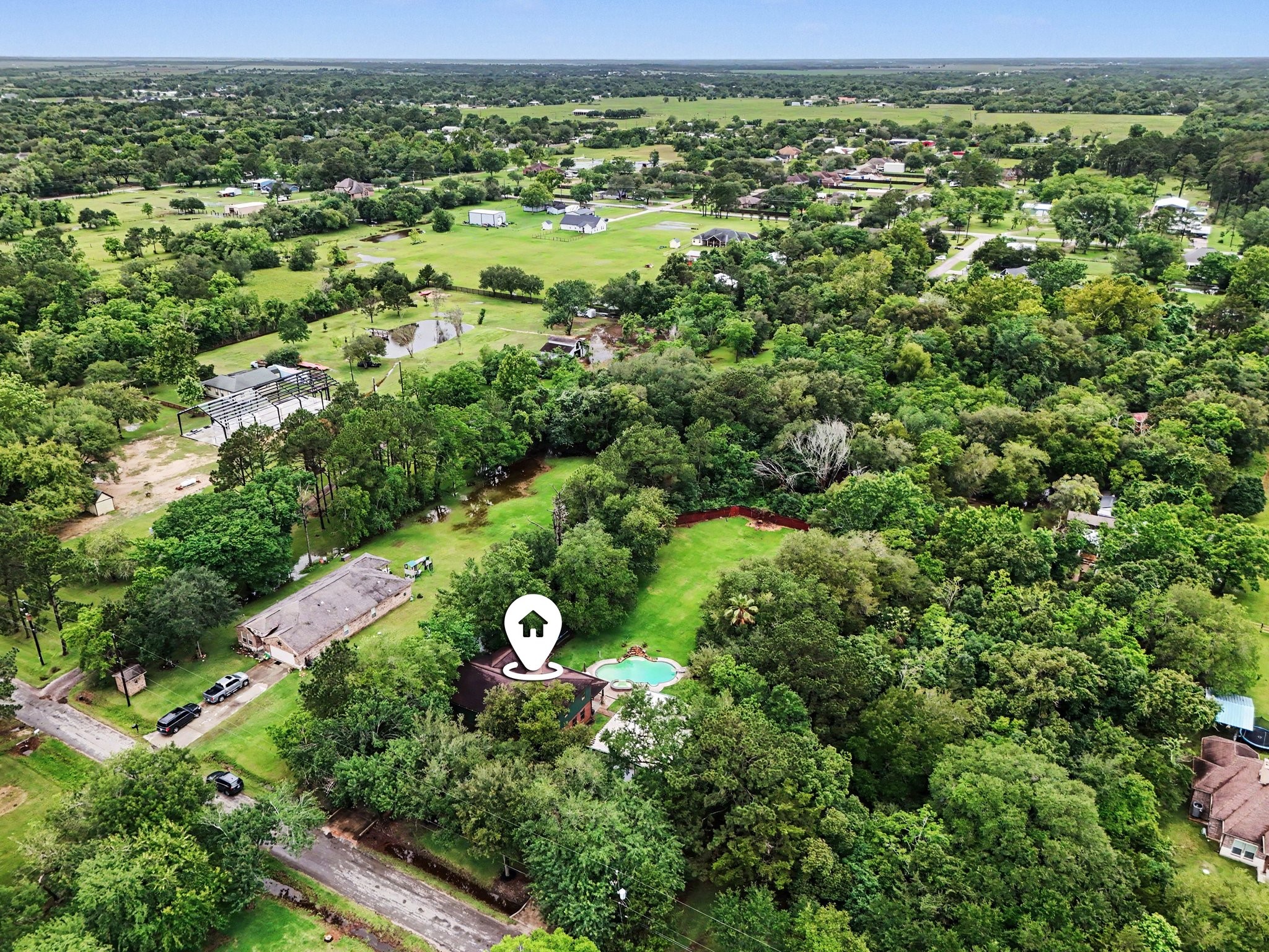 5104 Avenue R Santa Fe, TX 77510 - Photo 32 of 35 This aerial view showcases a spacious property surrounded by lush greenery, offering privacy and tranquility. The home features a pool and ample outdoor space, perfect for relaxation and entertainment. Nearby homes are spread out, emphasizing a peaceful, rural atmosphere.