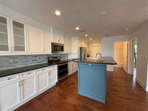 a kitchen with stainless steel appliances granite countertop a sink a stove and a refrigerator