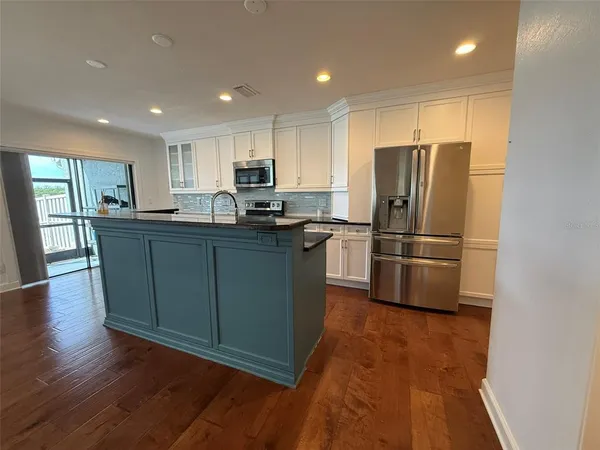 a kitchen with stainless steel appliances wooden floor and cabinets