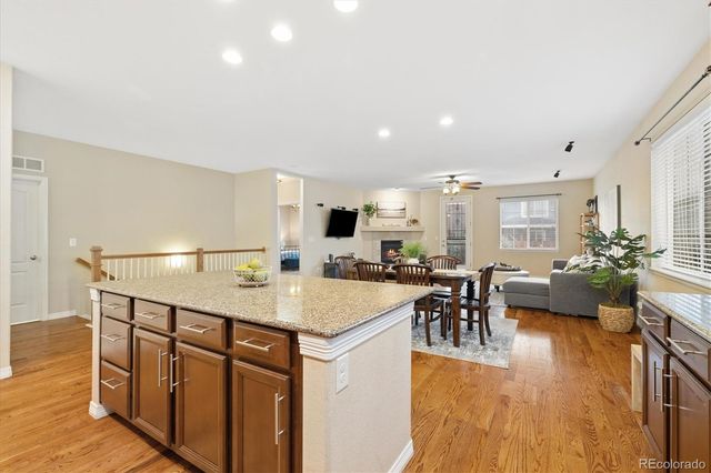 a kitchen with stainless steel appliances granite countertop a dining table chairs and wooden floor