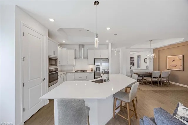 a kitchen with stainless steel appliances kitchen island granite countertop a dining table chairs refrigerator and microwave