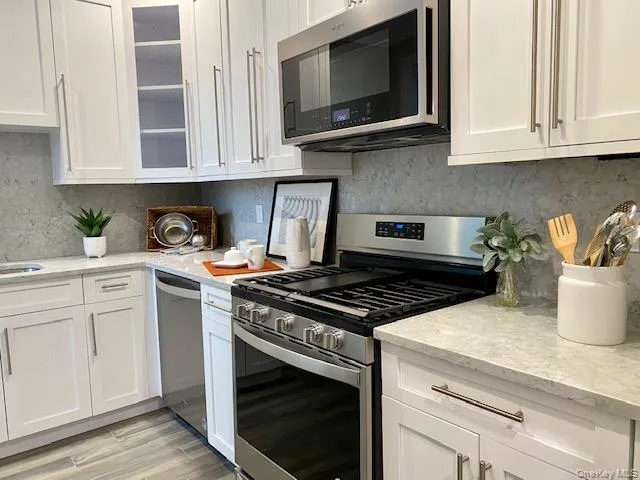 a kitchen with stainless steel appliances white cabinets and a stove top oven