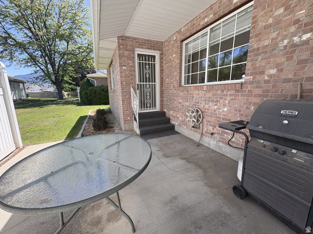 486 West 120 North Orem, UT 84057 - Photo 26 of 30 Paved patio area featuring a brick exterior wall, a large gridded window, and a white security screen door