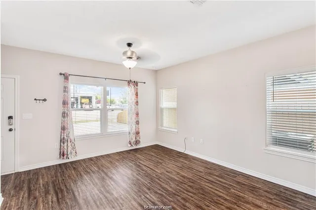 an empty room with wooden floor and windows