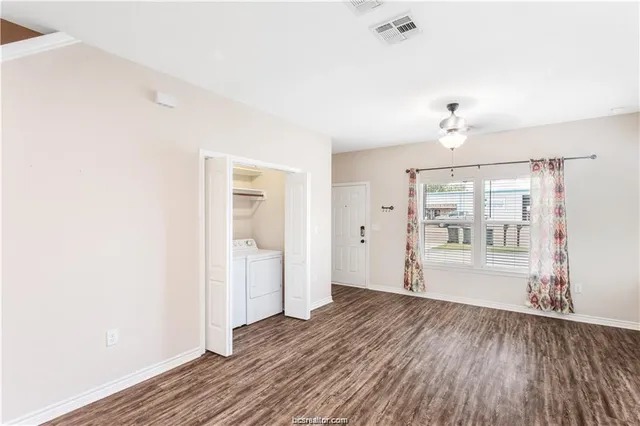 a view of an empty room with wooden floor and a window