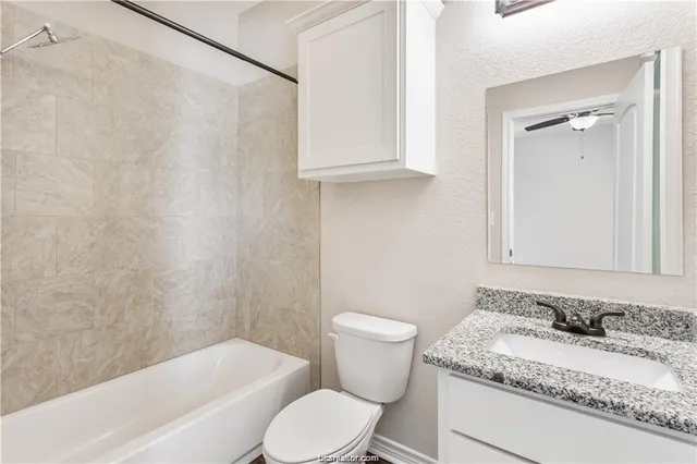 a bathroom with a granite countertop sink toilet and shower