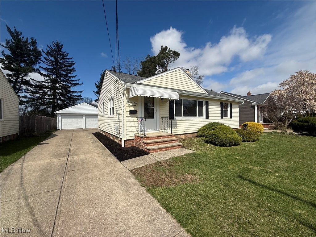 Bungalow-style home featuring an outbuilding, a front yard, fence, and a garage