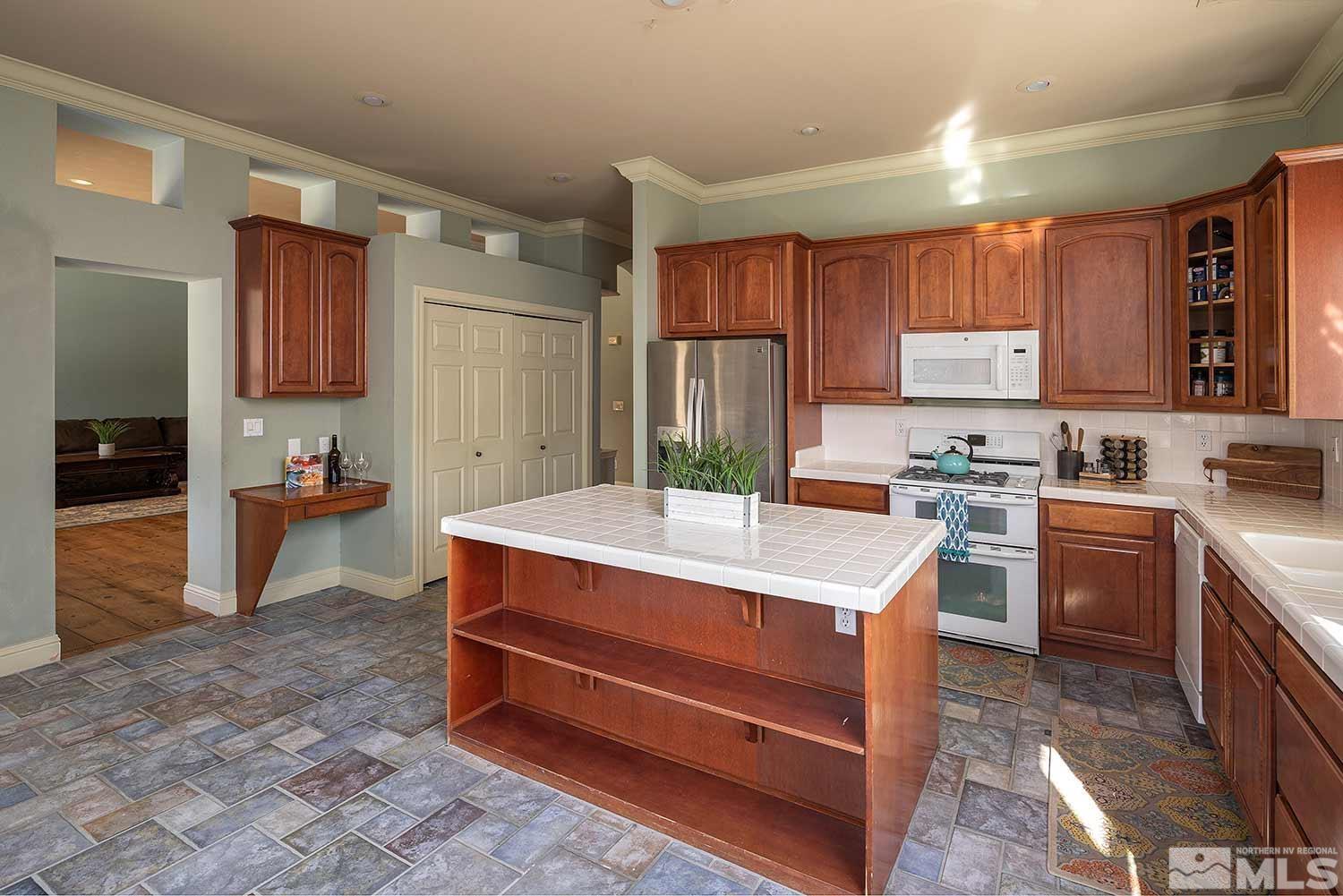 9785 Rolling Rock Court Reno, NV 89521 - Photo 12 of 35 a kitchen with kitchen island stainless steel appliances a stove refrigerator sink and cabinets