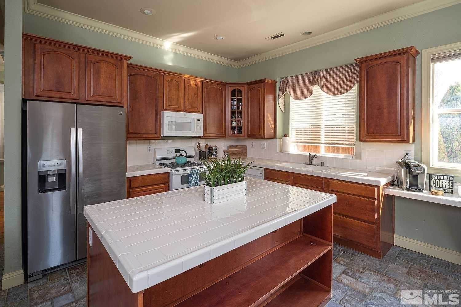 9785 Rolling Rock Court Reno, NV 89521 - Photo 10 of 35 a kitchen with a refrigerator a sink dishwasher a stove and white cabinets with wooden floor