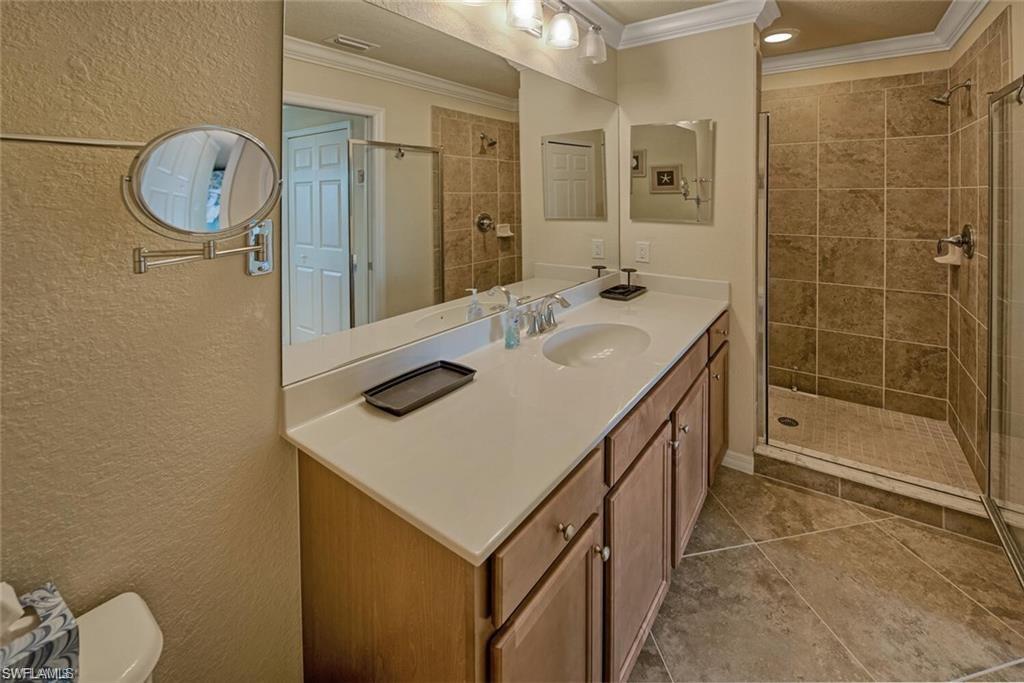 9731 Acqua Court, Unit 525 Naples, FL 34113 - Photo 12 of 35 Bathroom featuring ornamental molding, a stall shower, vanity, tile patterned floors, and a textured wall