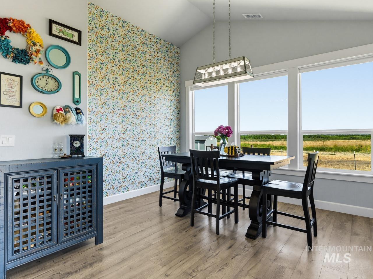 4950 West Columbia Road Nampa, ID 83687 - Photo 19 of 50 Dining area featuring wood-finish flooring, a vaulted ceiling, and a decorative accent wall