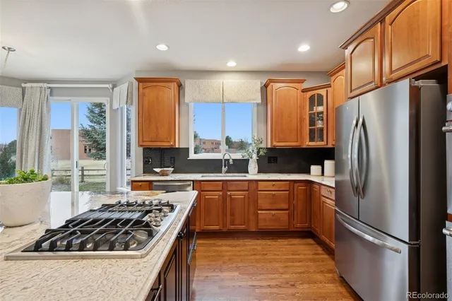 a kitchen with stainless steel appliances granite countertop a refrigerator a sink dishwasher a stove and a refrigerator