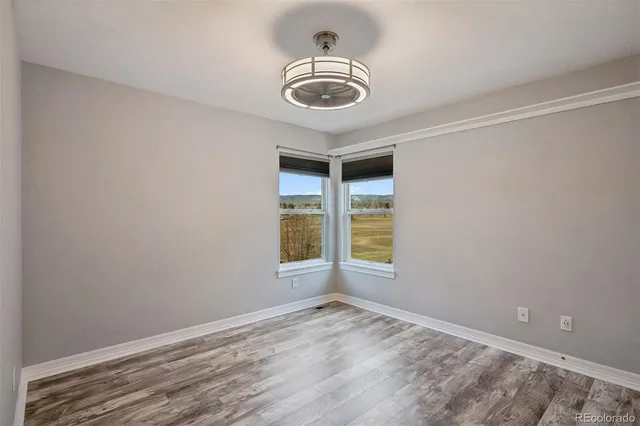 an empty room with a chandelier fan and windows