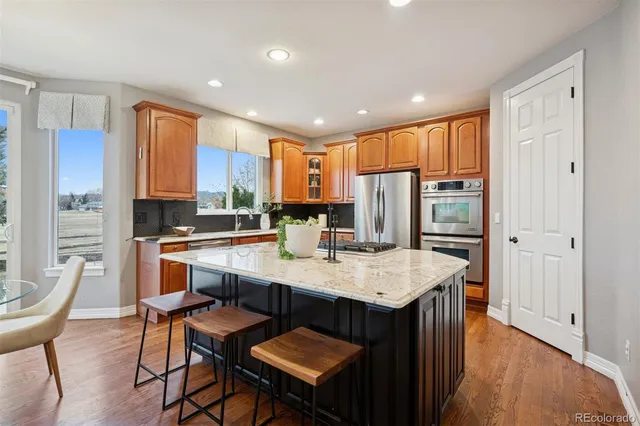 a kitchen with stainless steel appliances granite countertop a table chairs sink refrigerator and cabinets