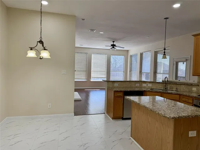 a kitchen with stainless steel appliances granite countertop a sink a refrigerator and a wooden floor