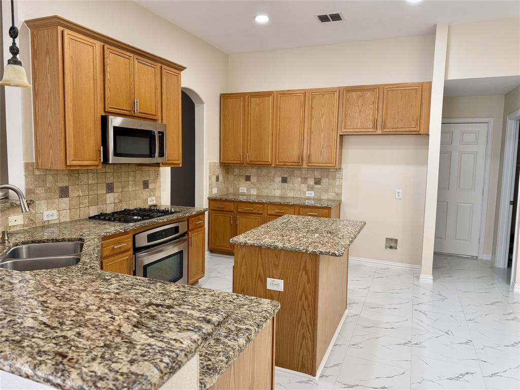 131 Fallkirk Drive Coppell, TX 75019 - Photo 5 of 20 a kitchen with stainless steel appliances granite countertop a stove top oven a sink and a refrigerator