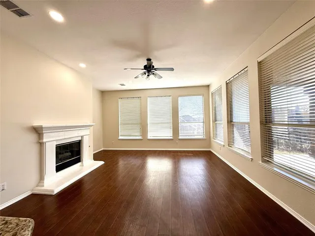 a view of an empty room with wooden floor fireplace and a window