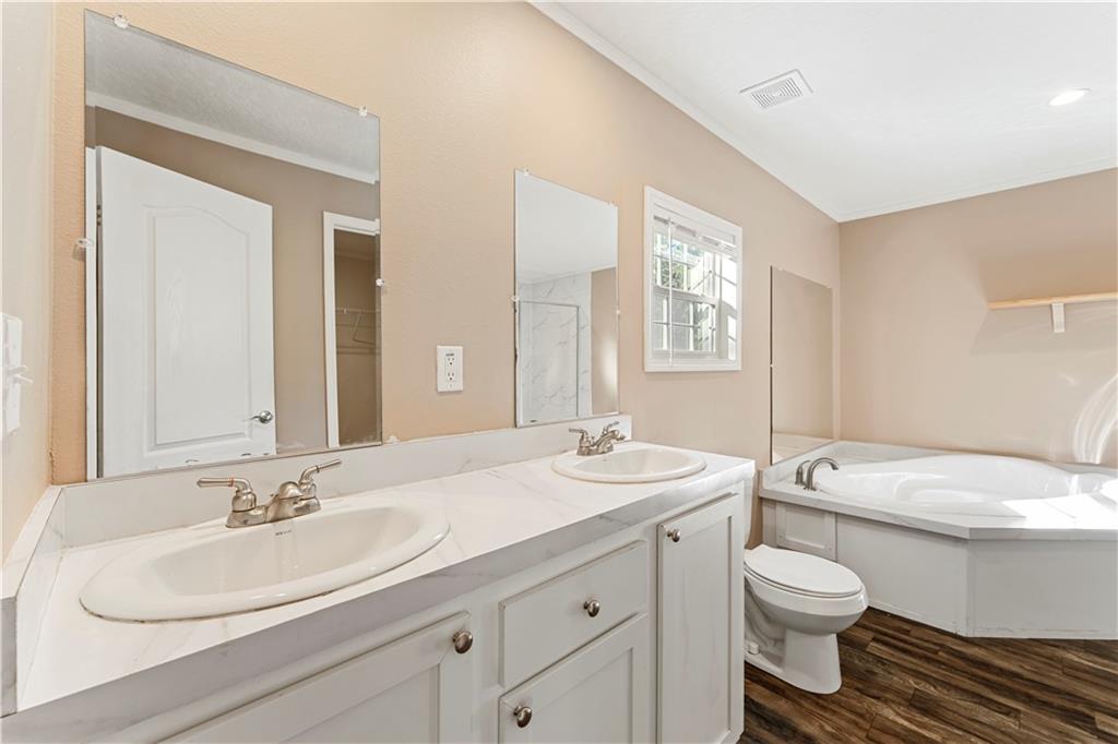 89 Ridge Road Seale, AL 36875 - Photo 23 of 46 Dual vanity with integrated sinks, wood-finish flooring, built-in corner tub, and window with privacy blinds