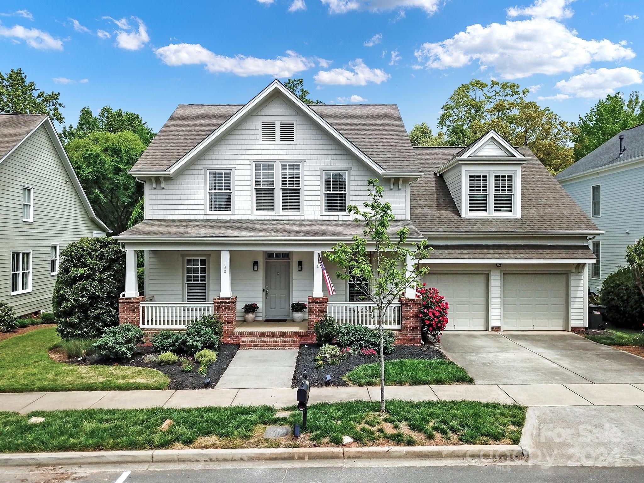 a front view of a house with a yard and potted plants