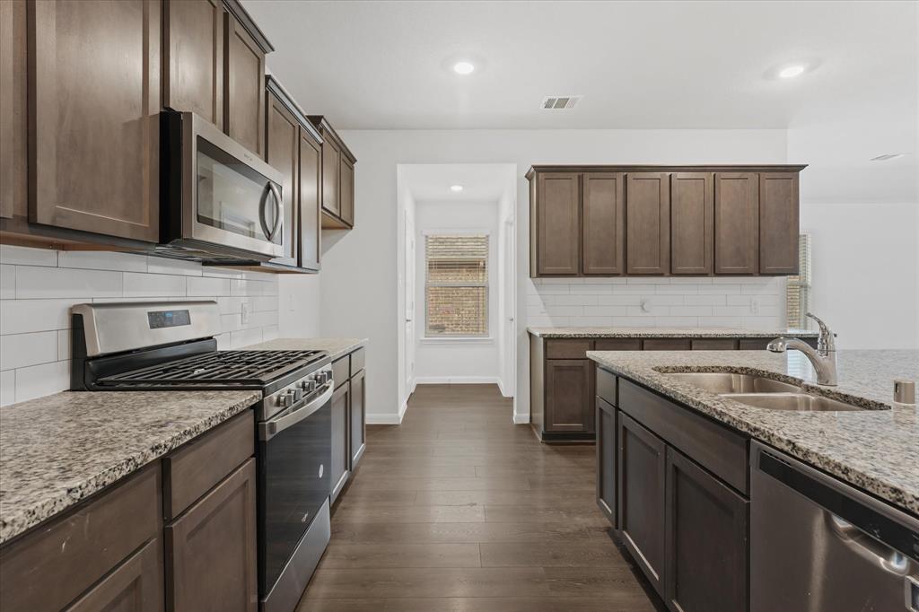 605 Spur Ridge Princeton, TX 75407 - Photo 7 of 30 a kitchen with stainless steel appliances granite countertop a stove a sink and a microwave