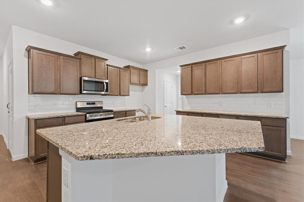 605 Spur Ridge Princeton, TX 75407 - Photo 9 of 30 a kitchen with granite countertop a sink and a stove top oven