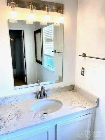 a bathroom with a granite countertop sink and a mirror