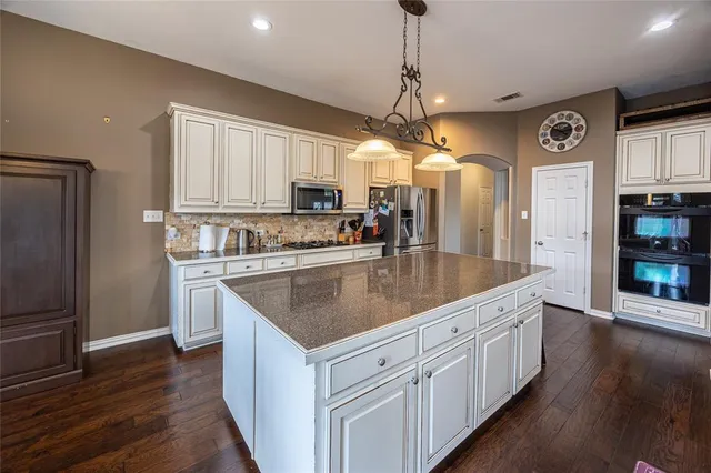 a kitchen with stainless steel appliances granite countertop a sink a refrigerator and a stove top oven
