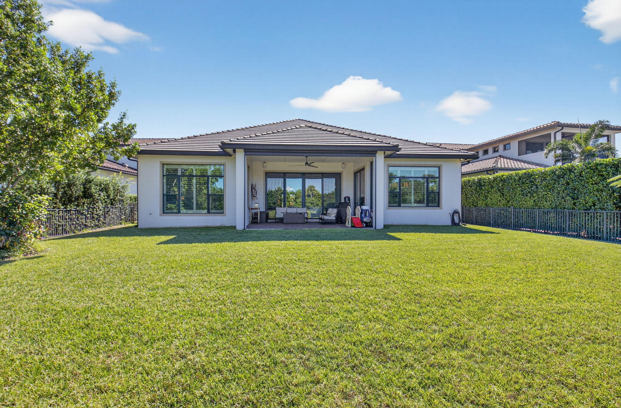 9331 Grand Prix Lane Boynton Beach, FL 33472 - Photo 52 of 96 a view of a house with floor to ceiling windows and a yard