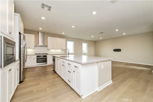 a large kitchen with stainless steel appliances a large counter top a stove a sink a refrigerator and cabinets